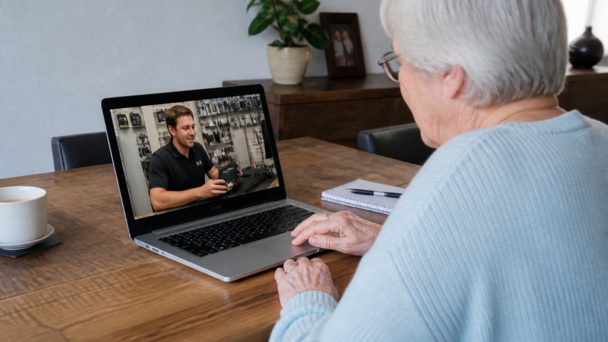 Oudere persoon krijgt via een videogesprek hulp op afstand bij het gebruik van een laptop door een IT-medewerker.